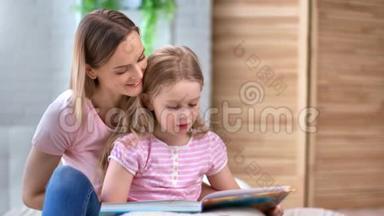 关爱的母亲在卧室里专心听可爱的女儿看书。 4k龙红相机